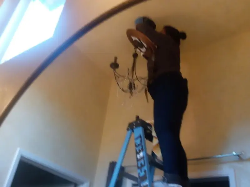 Electrician installing a chandelier in a Topeka residence
